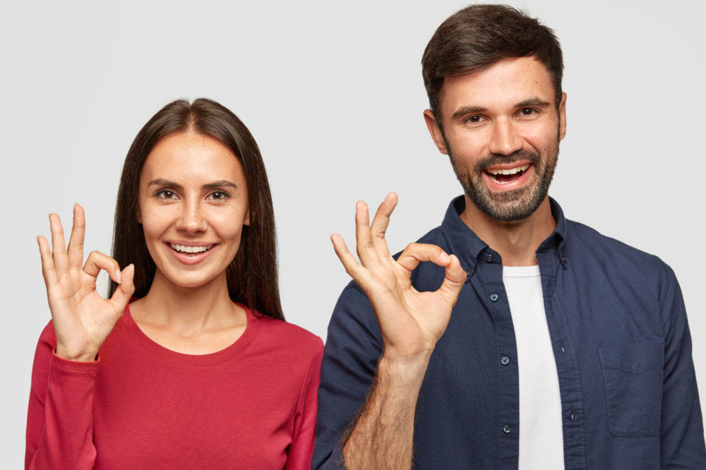 two friends showing ok sign with their hands on a white background