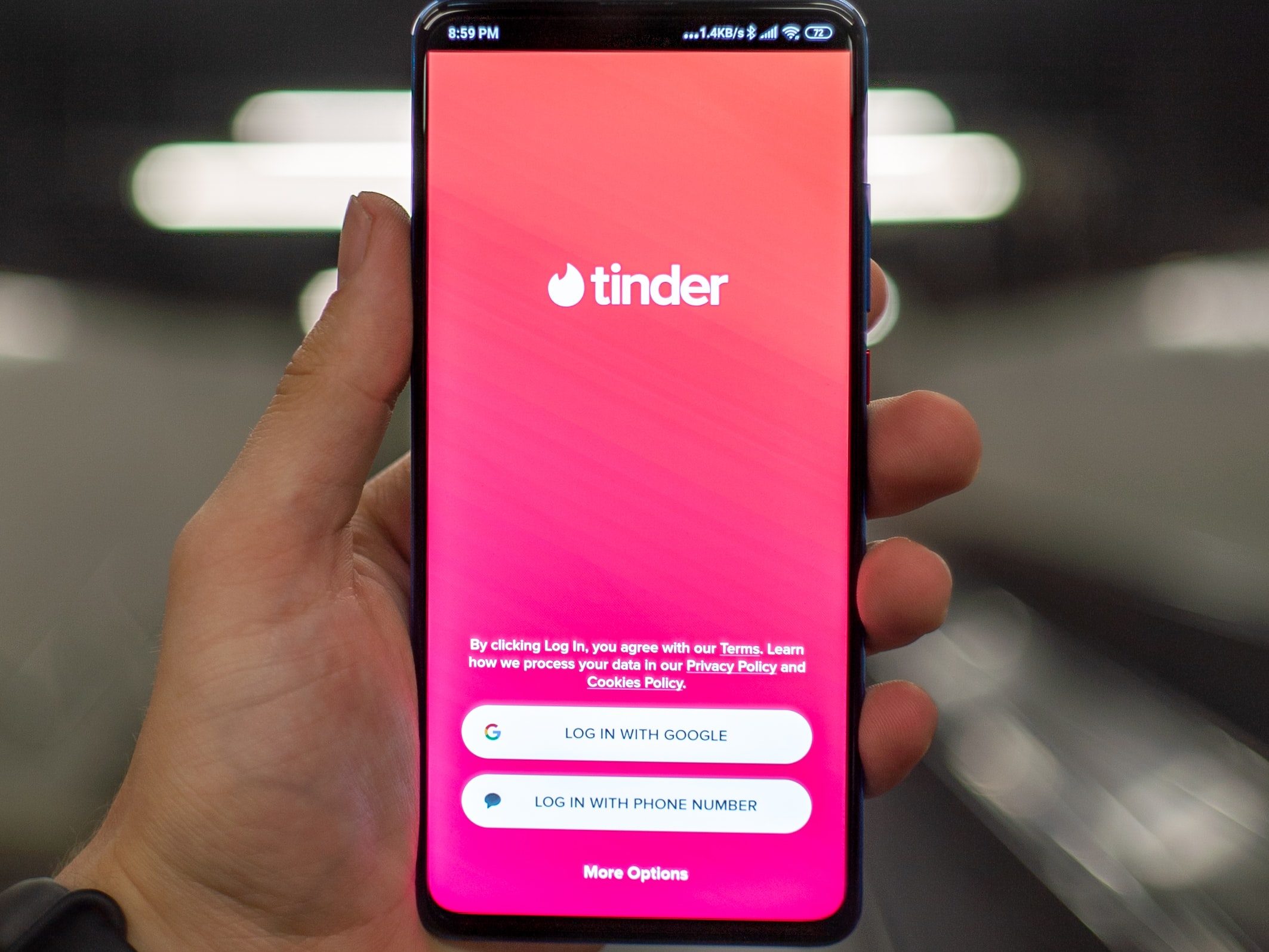 a hand holding phone with tinder application open